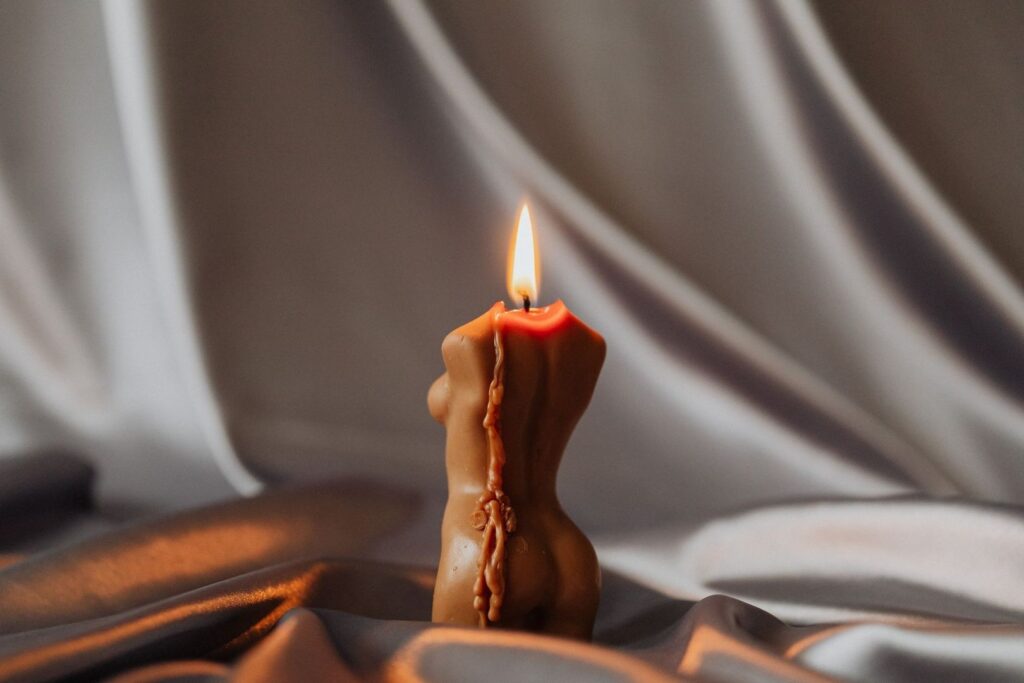 Lit wax sculpture melting on draped fabric in warm light