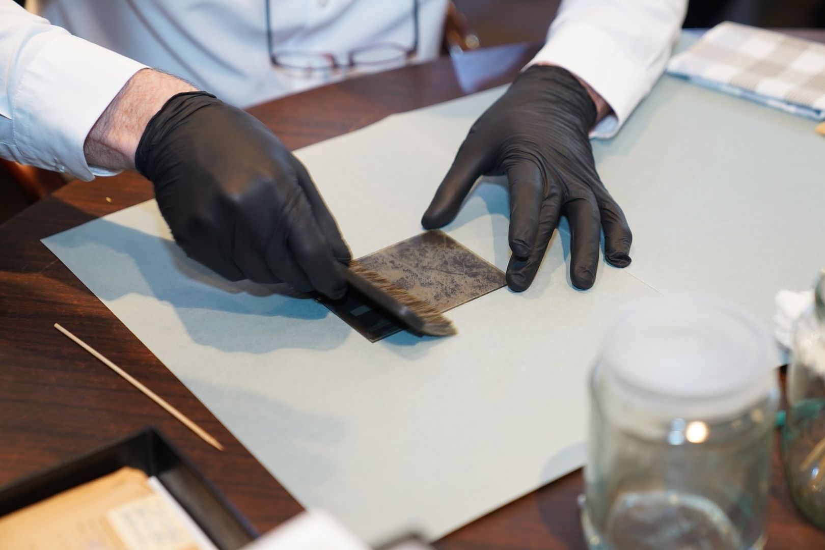 Gloved conservator examining a textured organic sample on a worktable
