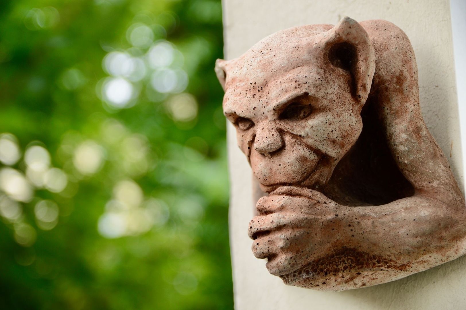 Grotesque stone face sculpture with exaggerated features and hands