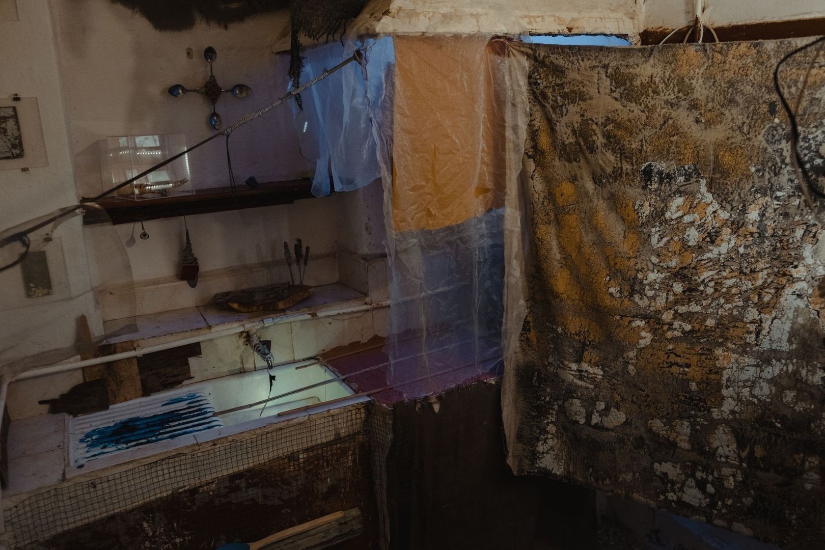 Weathered, cluttered studio interior with artwork and hanging materials
