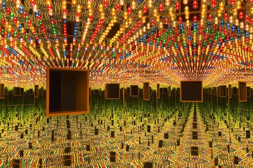 Mirrored room filled with colorful lights and suspended dark panels